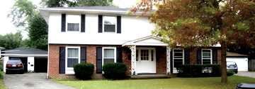 Tonawanda triplex for rent - A white house with a black car parked in front.