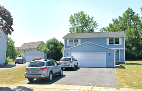 Amherst triplex for rent - A silver SUV is parked in front of a blue house.