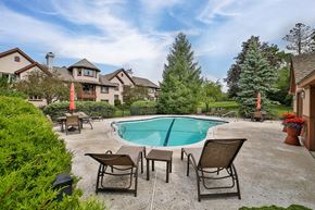 Williamsville condo for rent - A pool surrounded by patio furniture and trees.