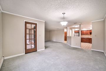 Williamsville condo for rent - A sparsely furnished living room with a carpeted floor and a ceiling fan.