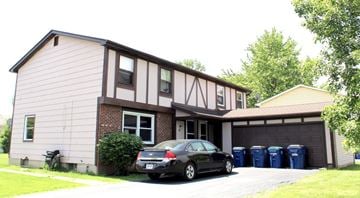 Amherst triplex for rent - A black car is parked in front of a house with a garage.