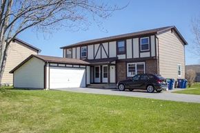 Amherst triplex for rent - A black car is parked in front of a two-story house.