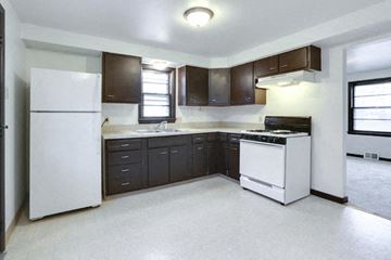 Blasdell house for rent - A kitchen with white appliances and dark brown cabinets.