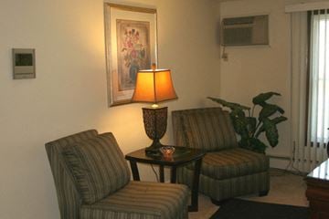 Buffalo apartment for rent - A living room with a striped chair and a table with a lamp on it.