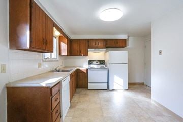 Amherst triplex for rent - A kitchen with white appliances and brown cabinets.