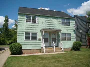 Buffalo triplex for rent - A green house with a white door and windows.
