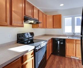 Amherst townhouse for rent - A kitchen with wooden cabinets and black appliances.