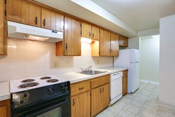 Tonawanda apartment for rent - A kitchen with wooden cabinets and a black stove top oven.