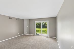 Amherst apartment for rent - A room with a carpeted floor and a sliding glass door leading to a green outdoor area.