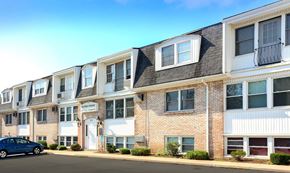 Kenmore apartment for rent - A blue car is parked in front of a row of townhouses.