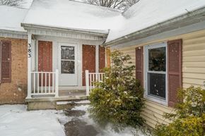 Amherst house for rent - A house with a white door and red shutters is covered in snow.