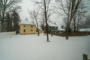 Amherst house for rent - A yellow house is surrounded by a snowy landscape.