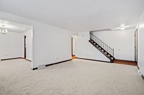 Amherst triplex for rent - A spacious room with a staircase and a chandelier.