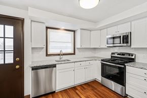 Amherst triplex for rent - A kitchen with white cabinets and stainless steel appliances.