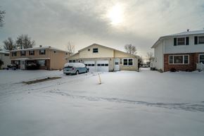 Amherst triplex for rent - A car is parked in front of a house on a snowy street.
