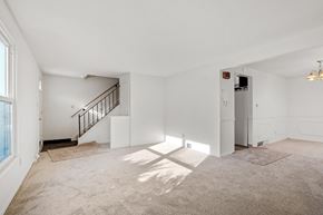 Amherst triplex for rent - A spacious, empty room with a staircase and a window.