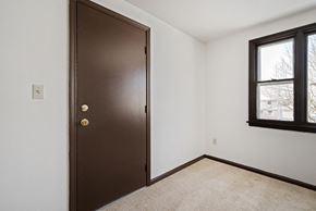 Amherst triplex for rent - A brown door with a gold handle is in a room with a carpeted floor and a window.