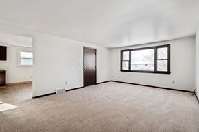 Amherst triplex for rent - A large, empty room with a carpeted floor and a window.