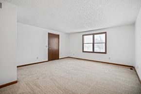 Amherst apartment for rent - A room with a carpeted floor, a door, and a window.