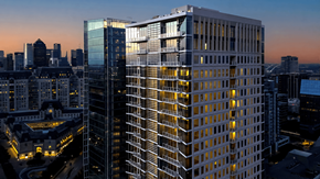 Dallas apartment for rent - A modern glass building stands tall among other buildings in a cityscape at dusk.