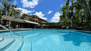 Lauderdale Lakes apartment for rent - A large swimming pool in front of a building with trees around.