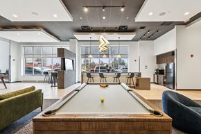 Pittsburgh apartment for rent - A pool table is in the middle of a room with a green couch and a blue chair.