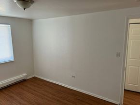 Denver apartment for rent - A room with a white wall and a wooden floor.
