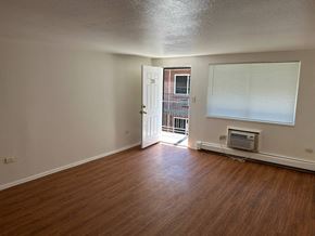 Denver apartment for rent - A room with wooden floors and a door leading to a balcony.
