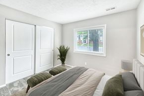 Cincinnati apartment for rent - A bedroom with a large bed and a window showing an outdoor view.