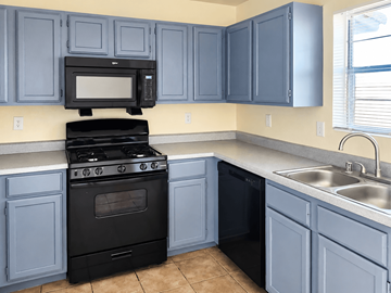 Anthony townhouse for rent - A kitchen with a black stove and blue cabinets.