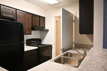 Chesapeake apartment for rent - A kitchen with a black refrigerator and a stove top oven.