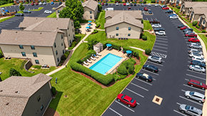 Arnold apartment for rent - A parking lot with cars and a swimming pool in the middle of a grassy area.