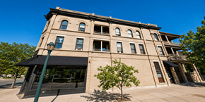 Denver apartment for rent - A large building with a black awning and a tree in front of it.
