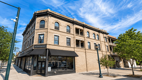 Denver apartment for rent - A large building with a black awning sits on a street corner.