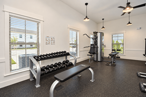 Haslet apartment for rent - A gym with a bench, weights, and a fan.