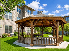 Dallas apartment for rent - A wooden gazebo is situated in a grassy area in front of a building.