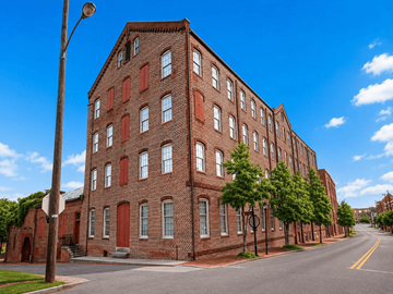 Petersburg apartment for rent - A long red brick building with many windows sits on a street corner.
