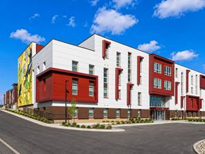 Denver apartment for rent - A modern building with a red and white facade and a yellow mural on the side.