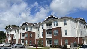 Greenville apartment for rent - a brick and white apartment building with cars parked in front