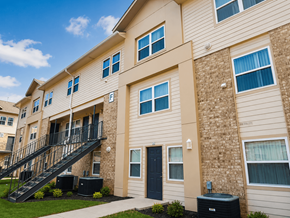 Shreveport townhouse for rent - A beige apartment building with a black door and a black staircase.