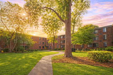 Columbus apartment for rent - A tree stands in front of a building with a walkway in between.
