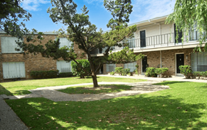 Houston apartment for rent - an exterior view of a building with a lawn and trees