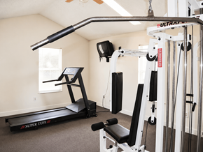 Hebron townhouse for rent - A home gym with a treadmill, weights, and exercise equipment.