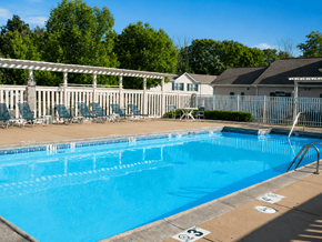 Hebron townhouse for rent - A blue swimming pool with a white fence and trees in the background.