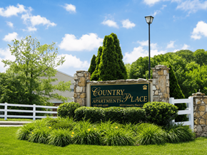Hebron townhouse for rent - A sign for Country Apartments Place is surrounded by greenery.