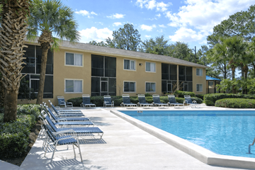 Jacksonville apartment for rent - A pool area with chairs and a building in the background.