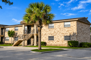 Jacksonville apartment for rent - A stone building with a palm tree in front.