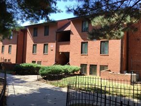 Baltimore apartment for rent - A red brick building with a black fence in front.