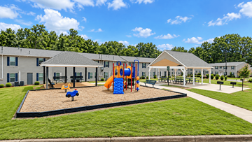 Newnan apartment for rent - A playground area with a slide and sandbox in front of a building.