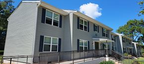 Newnan apartment for rent - a gray apartment building with a balcony and a blue sky